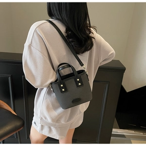 Détail du sac seau noir à texture gaufrée avec clous dorés et bandoulière réglable