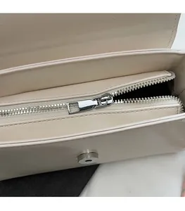 Close-up of internal silver zipper and smooth hardware on creamy white leather handbag