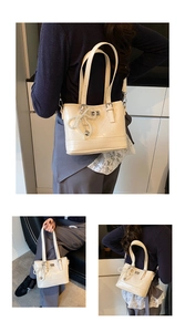 Detailed close-up of quilted off-white bucket bag with a pearl bow charm and stitching