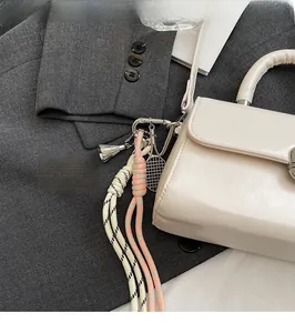 Detail of minimalist cream square bag with metal badminton and tennis racket charms
