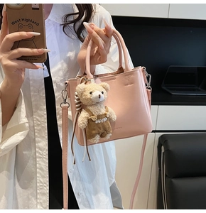 Detailed close-up of pink oil wax leather bucket bag with a cute plush bear pendant accessory