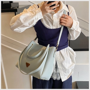 Detail of light blue lychee pattern leather bucket bag with gold metal handle and strap