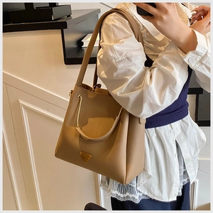 Detail of khaki litchi grain leather bucket bag with gold U-shaped metal handle