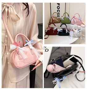 Detail view of lace trim and plaid bow on mini patent leather Boston handbag for women