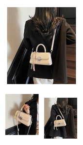 Close-up of minimalist cream crossbody bag with metal lock and woven tassel detail