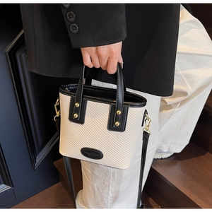 Détail du sac seau tissé avec bordures en cuir noir et rivets dorés élégants