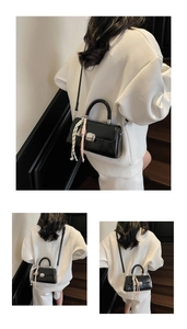 Close-up of black leather crossbody bag with silver hardware and striped silk scarf detail