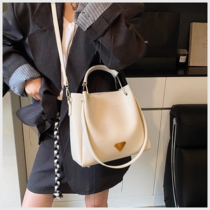 Close-up of cream lychee texture leather bucket bag with gold triangle logo and strap