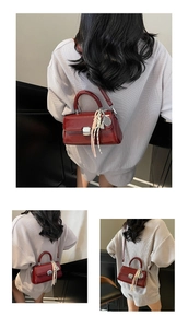 Detail of dark red glossy leather crossbody bag with silver buckle and silk scarf tassel