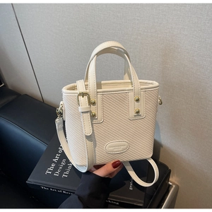 Détail du sac seau tissé avec rivets dorés et plaque ovale de mode élégante
