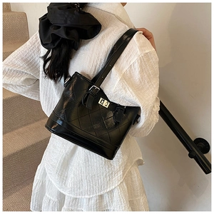 Detail of black quilted shoulder bag featuring a silver twist lock and glossy leather texture