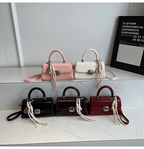 Close-up of five minimalist patent leather mini square handbags in various colors
