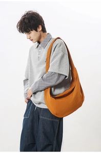Detail of large orange nylon crescent crossbody bag worn by model for casual daily use
