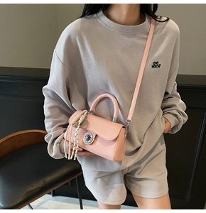 Gros plan d'un mini sac carré rose brillant avec fermoir argenté et pompon tressé