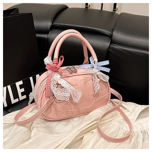 Detailed view of pink patent leather Boston bag with decorative bows and lace trim