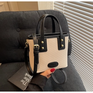 Détail de la texture tissée et des rivets dorés sur le sac seau crème élégant