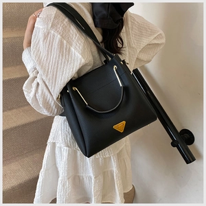 Detail shot of black lychee-textured bucket bag with gold hardware and logo triangle