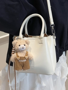 Minimalist white bucket bag in waxed leather texture with a cute teddy bear charm