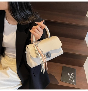 Détail d'un sac à main chic en cuir verni crème avec fermoir argenté et foulard en soie