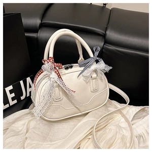 Close-up of cream Boston bag featuring decorative lace bows and adjustable strap details