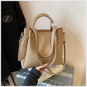Detail of khaki lychee grain tote bag featuring gold hardware on silver suitcase