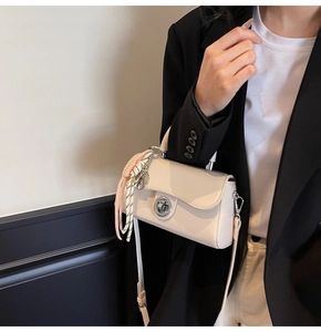 Détail du sac à main beige minimaliste avec fermoir rotatif argenté et foulard en soie
