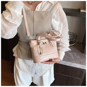 Close-up of pink quilted bucket bag with pearl bow and metal heart charm detail