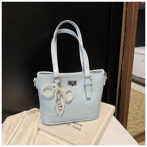 Close-up of light blue quilted PU leather bag with silver lock and pearl bow charm