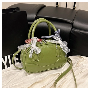 Detail of green glossy Boston bag with white lace bow and checkered ribbon decoration