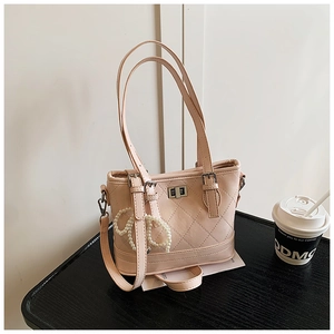 Close-up of quilted bucket bag with silver metal twist lock and pearl bow charm