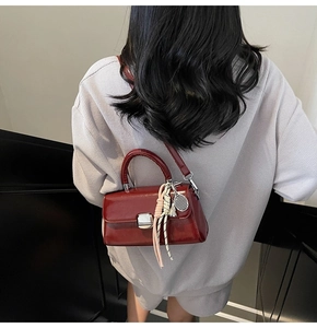 Detail of red patent leather handbag with silver lock and tennis racket charm