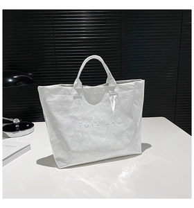 Detail of white Dupont paper tote bag with unique crinkled texture and embossed TOTE BAG text