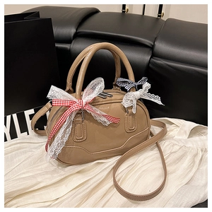Detail of glossy beige patent leather mini Boston bag with charming lace bow charms