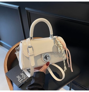 Détail d'un sac à main en cuir verni blanc crème avec un pendentif sport créatif