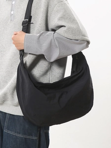 Large black nylon crescent crossbody bag with adjustable strap worn by model on white background