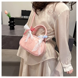 Pink Boston bag with white lace trim and plaid bow detail shown on a model's shoulder