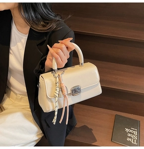 Detail of cream leather handbag with silver metallic clasp and woven rope ornament