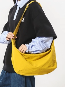 Bright yellow large nylon crescent crossbody bag worn by a model for a stylish casual look