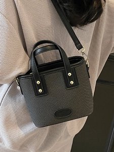 Sac seau tissé noir chic avec clous dorés et bandoulière réglable porté par un mannequin