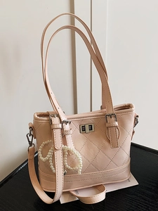 Elegant quilted bucket bag in light apricot with pearl bow accent and metallic twist lock