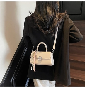 Chic cream mini leather square bag with silver clasp shown on black outfit with tassel