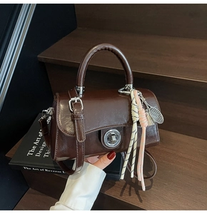 Détail du sac vintage en cuir ciré marron avec fermoir rotatif et charm de tennis