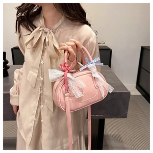 Detail of pink glossy handbag with white lace trim and plaid bows on beige outfit