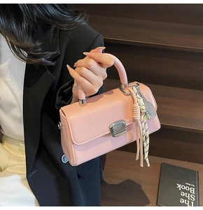 Detail of pink patent leather handbag with stylish fabric tassel and metal buckle