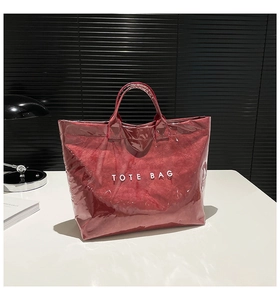 Detail of red tote bag with transparent PVC layer and bold white TOTE BAG text