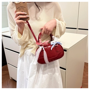 Close-up of a red patent leather mini bowling bag with colorful bow charms for women