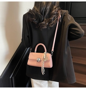 Detail of pink leather handbag with silver clasp and decorative tennis racket charm