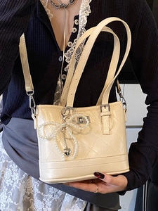 Chic quilted cream bucket bag with pearl bow charm and silver twist lock closure