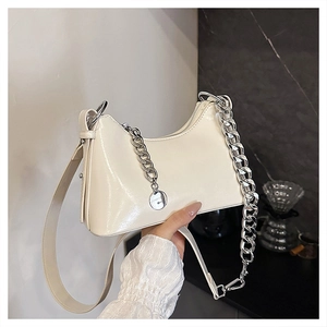 Detail of creamy white crescent shoulder bag with silver chain and smooth leather texture