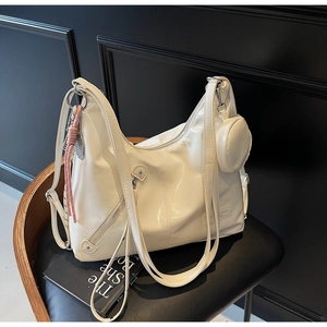 Detail of a large cream-colored patent leather hobo bag with a matching mini round pouch